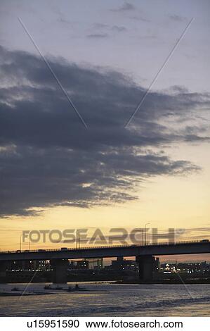 Stock Image - Bridge over river at dusk, Tokyo Prefecture, Honshu, Japan. Fotosearch