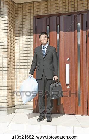 Businessman standing in front of house holding garbage bag, Hyogo Prefecture, Honshu, Japan View Large Photo Image Stock Image - Businessman standing in front of house holding garbage bag, Hyogo Prefecture, Honshu, Japan. Fotosearch