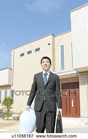 Stock Photo - Businessman walking holding garbage bag, Hyogo Prefecture, Honshu, Japan. Fotosearch