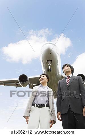Stock Image - Businesspeople Below Airplane. Fotosearch