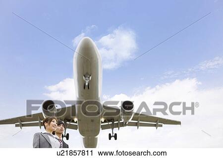 Stock Image - Businesspeople Below Airplane. Fotosearch