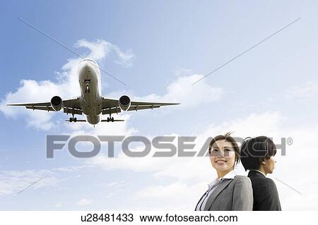 Stock Image - Businesspeople Below Airplane. Fotosearch