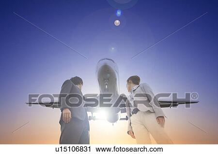Stock Image - Businesspeople Looking Back at Airplane. Fotosearch