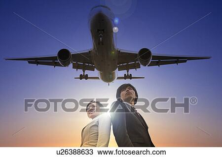 Stock Image - Businesspeople Looking Back at Airplane. Fotosearch