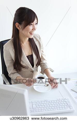 Businesswoman at her desk drinking coffee View Large Photo Image Stock Image - Businesswoman at her desk drinking coffee. Fotosearch