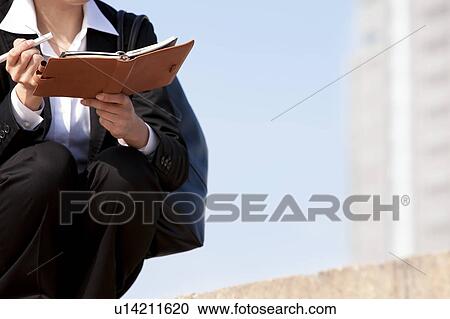Businesswoman crouching holding diary and pen, Midsection View Large Photo Image Stock Image - Businesswoman crouching holding diary and pen, Midsection. Fotosearch