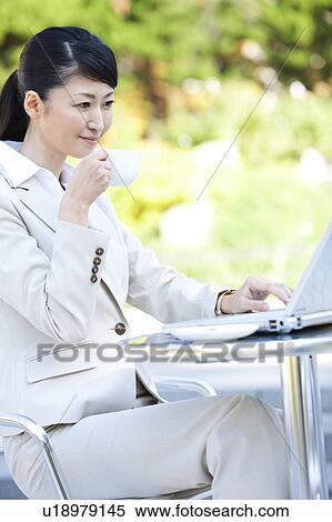Businesswoman drinking coffee and using laptop View Large Photo Image Stock Photography - Businesswoman drinking coffee and using laptop. Fotosearch