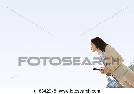 Businesswoman holding a cell phone and looking up View Large Photo Image Stock Photo - Businesswoman holding a cell phone and looking up. Fotosearch