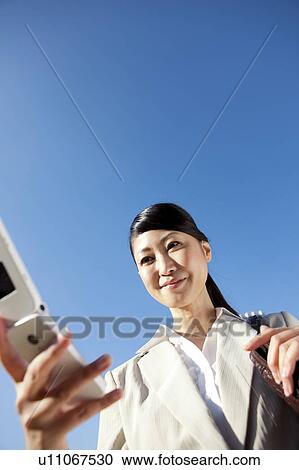 Businesswoman holding a cell phone View Large Photo Image Stock Image - Businesswoman holding a cell phone. Fotosearch