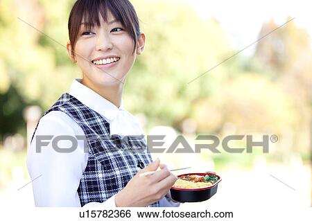 Stock Photograph - Businesswoman holding chopsticks and lunchbox. Fotosearch