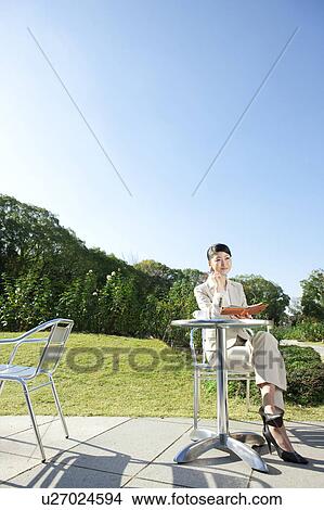 Picture - Businesswoman holding diary and pen contemplating. Fotosearch