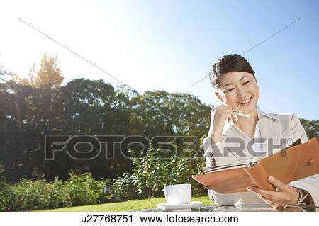 Stock Image - Businesswoman holding diary and pen. Fotosearch