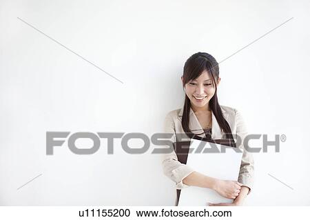Stock Image - Businesswoman holding ring binders. Fotosearch