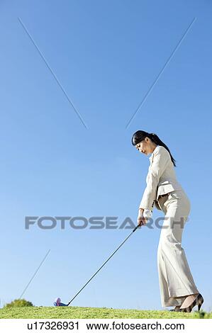 Stock Image - Businesswoman in suit playing golf. Fotosearch