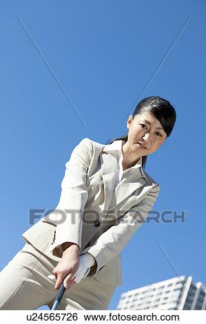 Stock Photograph - Businesswoman in suit playing golf. Fotosearch