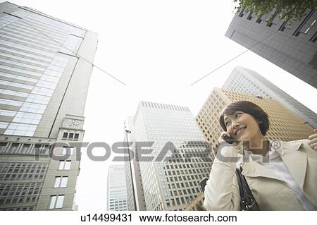 Stock Image - Businesswoman on cell phone, Low Angle View. Fotosearch