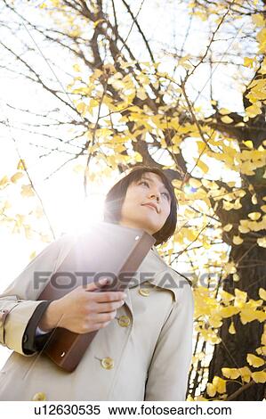 Stock Photography - Businesswoman standing holding ring binder. Fotosearch