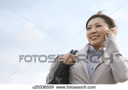Stock Photo - Businesswoman talking on cell phone, low angle view. Fotosearch