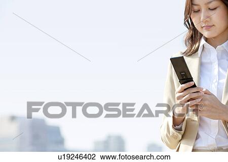 Businesswoman using a cell phone on rooftop View Large Photo Image Stock Image - Businesswoman using a cell phone on rooftop. Fotosearch