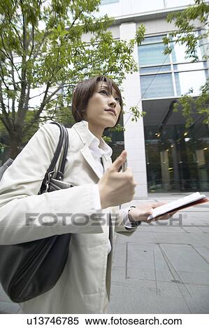 Businesswoman walking and holding a diary View Large Photo Image Stock Photography - Businesswoman walking and holding a diary. Fotosearch