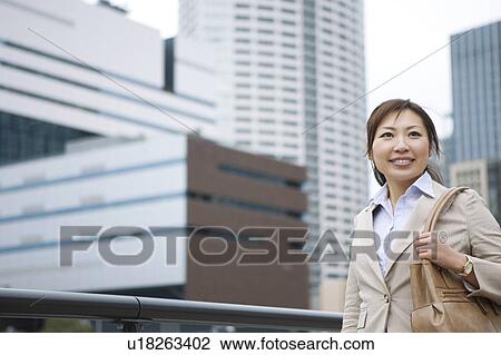 Stock Image - Businesswoman walking in financial district. Fotosearch