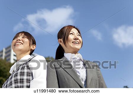Stock Image - Businesswomen standing side by side smiling. Fotosearch