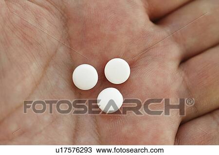 Stock Image - Close-up of pills on hand. Fotosearch