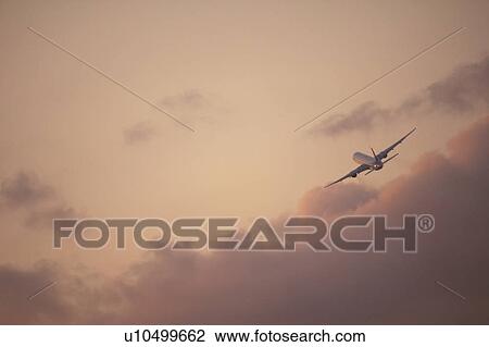 Stock Image - Commercial airplane flying at dusk, Japan. Fotosearch