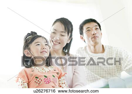 Stock Photograph - Family sitting on sofa. Fotosearch