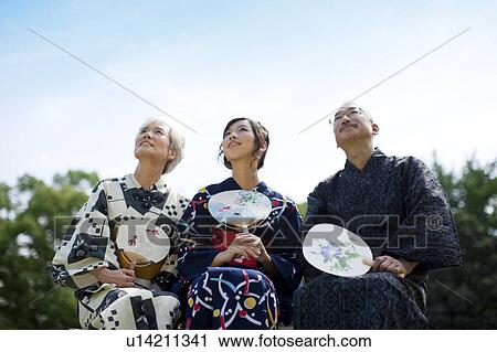 Stock Image - Family wearing Yukata and sitting on bench. Fotosearch