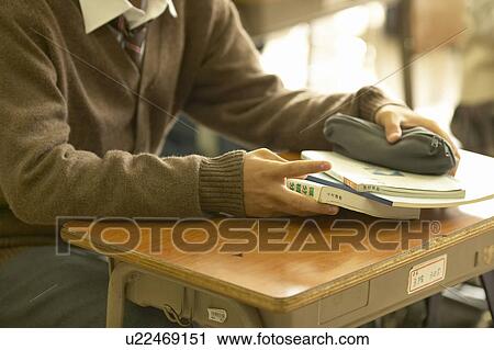 Stock Image - High school boy holding textbooks and pencil case, Japan. Fotosearch