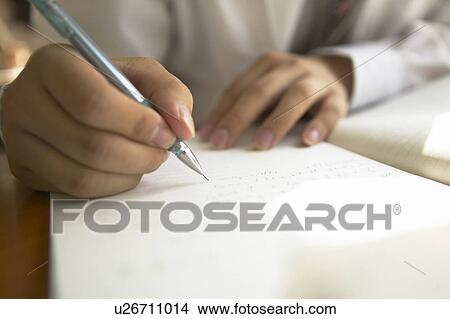 Picture - High school boy writing on note pad, Japan. Fotosearch