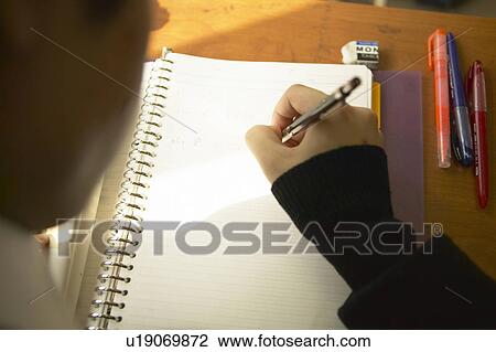 Stock Image - High school boy writing on note pad, Japan. Fotosearch