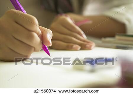 Picture - High school girl writing on note pad, Japan. Fotosearch