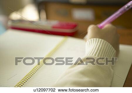 Stock Image - High school girl writing on note pad, Japan. Fotosearch