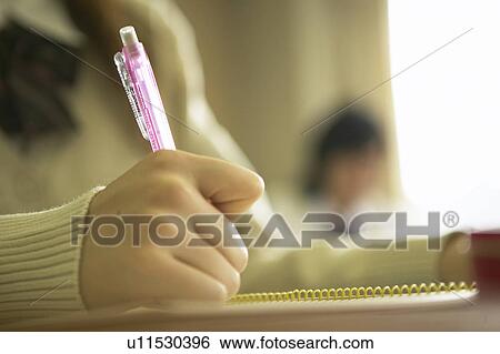Stock Photograph - High school girl writing on note pad, Japan. Fotosearch