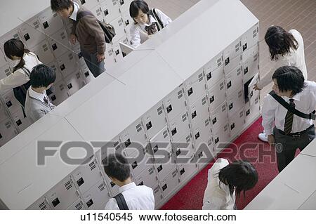Stock Photography - High school student at locker changing shoes, Japan. Fotosearch