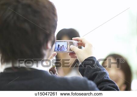 Stock Image - High school students taking picture with mobile phone, Japan. Fotosearch