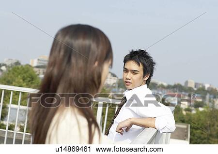 Stock Image - High school students talking on rooftop, Japan. Fotosearch