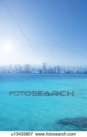 Stock Photo - Sea, cityscape and rainbow, digital composite. Fotosearch