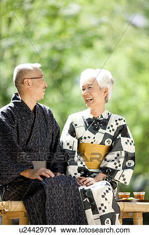 Picture - Senior couple wearing Yukata sitting on bench. Fotosearch