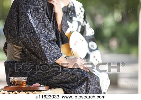 Stock Image - Senior couple wearing Yukata sitting on bench. Fotosearch