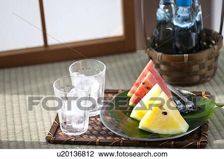 Stock Image - Slices of watermelons and glasses with ice cubes inside. Fotosearch