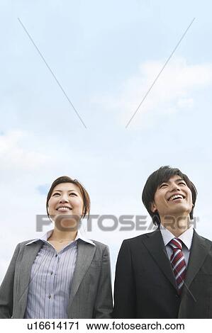 Stock Image - Two Businesspeople Against Blue Sky. Fotosearch