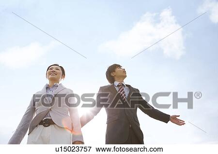 Stock Photo - Two Businesspeople Against Blue Sky. Fotosearch
