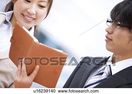 Stock Image - Two Businesspeople Looking at Diary. Fotosearch