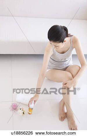 Stock Photograph - Woman holding bottle of massage oil. Fotosearch