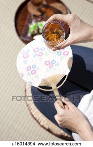 Picture - Woman holding glass of barley tea. Fotosearch