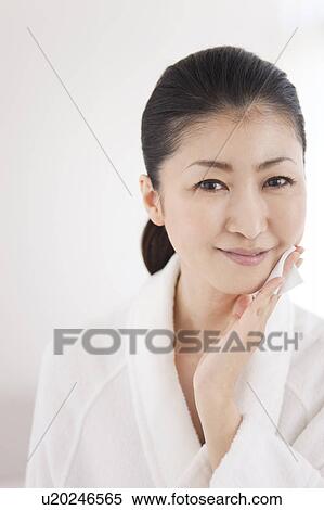 Woman in bathrobe putting lotion on face View Large Photo Image Stock Photography - Woman in bathrobe putting lotion on face. Fotosearch