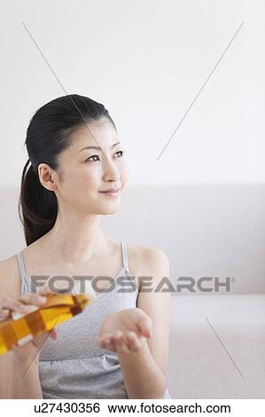 Stock Photograph - Woman pouring massage oil into hand. Fotosearch